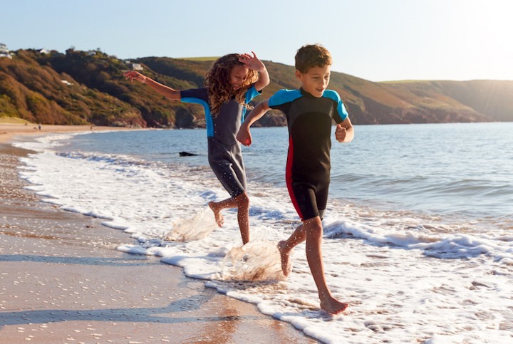 Aqua Wear Shop -Aqua Wear Shop Two kids in wetsuits running along the shore optimised